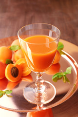 Glass of apricot juice and fresh fruits on table close up