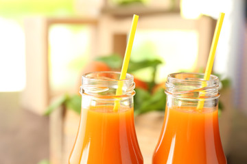 Bottles of apricot juice and fresh fruits on table close up