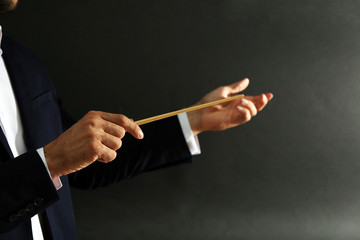 Music conductor hands with baton on black background