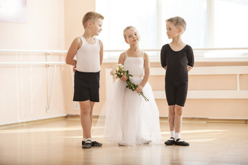 Obraz premium At ballet dancing class: young boys and a girl with flowers posing gracefully