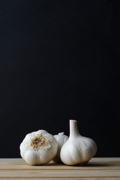 Garlic Bulbs  on Wood Plank Table with Black Background