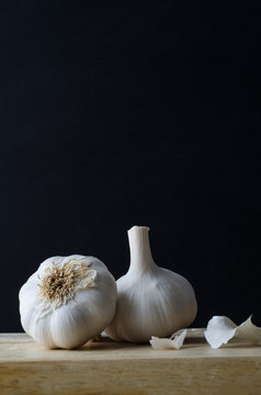 Two Garlic Bulbs on Wooden Chopping Board