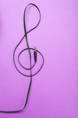 Clef of headphones cable on purple background