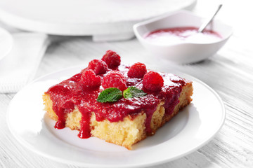 Fresh pie with raspberry jam in white saucer on wooden table, closeup