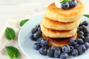 Fritters of cottage cheese with blueberries in plate, closeup