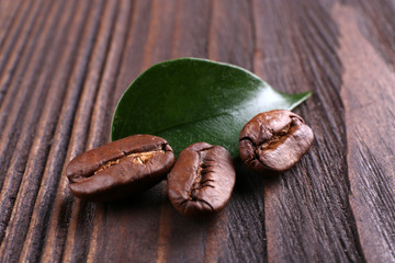Coffee beans with leaf on wooden background