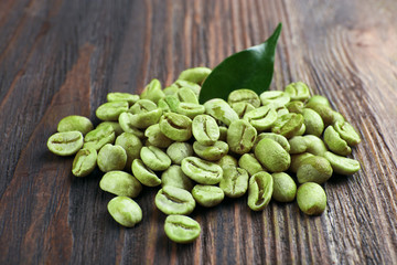 Green coffee beans with leaf on wooden background