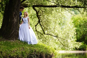 Obraz na płótnie Canvas Happy bride and groom on their wedding near lake