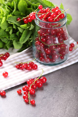 Fresh red currants in jar with mint on table close up
