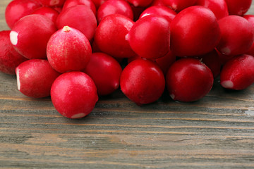 Heap of fresh radishes on wooden table close up background