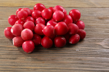 Heap of fresh radishes on wooden table close up background