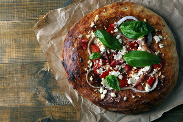 Greek homemade pizza with ham,onion, roasted tomato, creamy feta on wooden table background