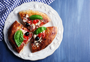 Pieces of homemade pizza on plate, on color table background