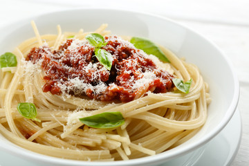 Spaghetti Bolognese with parmesan cheese in white bowl, on color wooden background