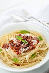 Spaghetti Bolognese with parmesan cheese in white bowl, on color wooden background