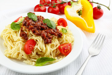 Spaghetti Bolognese on white plate, on color wooden background