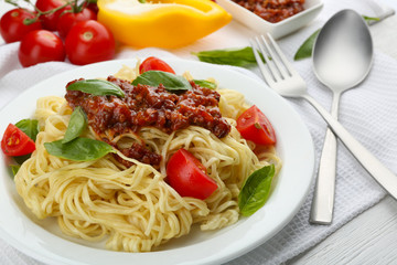 Spaghetti Bolognese on white plate, on color wooden background