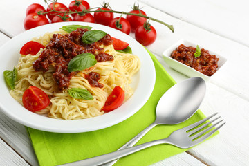 Spaghetti Bolognese on white plate, on color wooden background