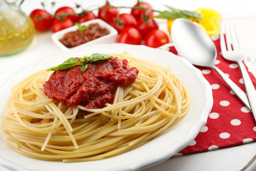 Spaghetti with tomato sauce and cheese on white plate, on color wooden background