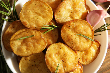 Delicious baked potato with rosemary in bowl close up