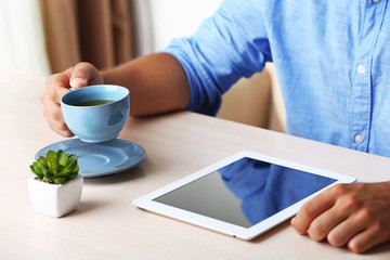 Fototapeta na wymiar Man with digital tablet on wooden table background