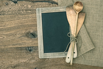 Retro kitchen utensils and vintage blackboard on wooden backgrou