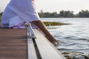 Mujer sentada en el embarcadero con los pies en el agua y las uñas pintadas de rojo una tarde de verano. Disfrutando de las vacaciones. Relax y descanso.
