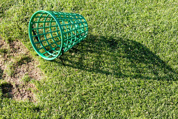 Green plastic empty bucket at a driving range on a golf course