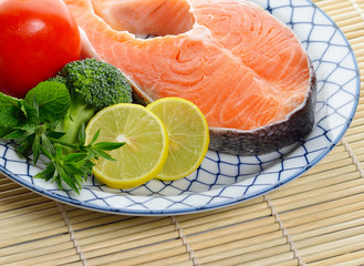 fresh salmon fillet with vegetables and lemon slices.