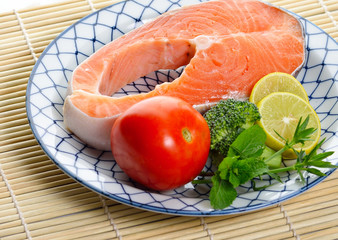 fresh salmon fillet with vegetables and lemon slices.