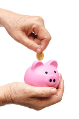 old female elderly hand putting a golden coin into a saving piggy bank - saving money for retirement concept