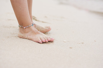 Fototapeta na wymiar Barefoot child with ankle bracelet on beach