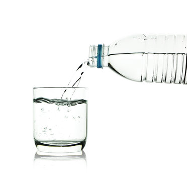 Drinking water is poured from a bottle into a glass with clippin