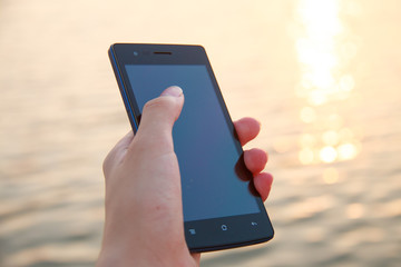 Hand holding smart phone against water