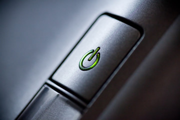Green glowing power button. Closeup