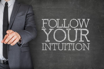 Fototapeta na wymiar Follow your intuition on blackboard with businessman