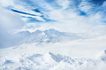 Winter snow-covered mountains and blue sky with white clouds