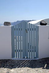 blue wooden gates in white house, Santorini island, Greece
