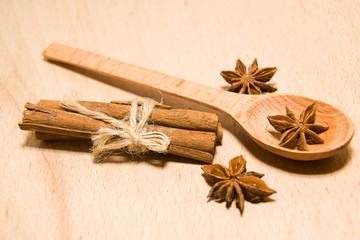 Spoon, cinnamon and star anise on a wooden surface