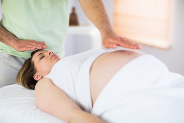 Obraz na płótnie Canvas Relaxed pregnant woman getting reiki treatment