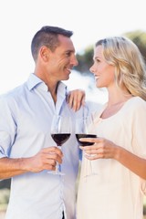 Smiling couple embracing, holding wineglass and looking at each other