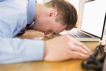 Stressed businessman with head on laptop