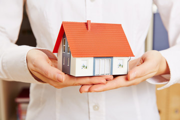 Hände halten Haus als Versicherung