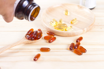 Closeup soft gelatin supplement fish oil capsule on wooden