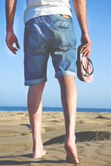 young man walking down a dune