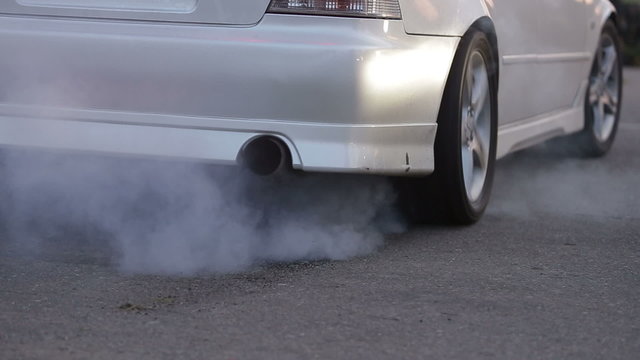 white drift cars burnin tires on the pavement, rear view