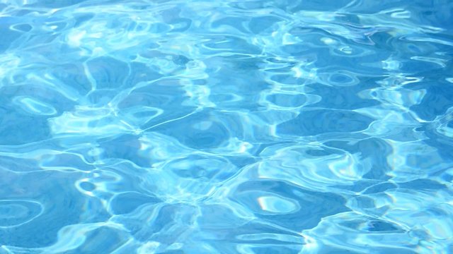 Water surface with rippling waves in the pool. On the water surface are reflections from the sun.