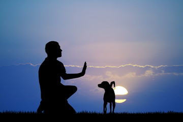 man training dog at sunset