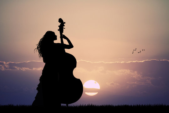 woman plays the double bass at sunset