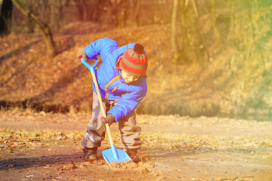 little boy digging in autumn park